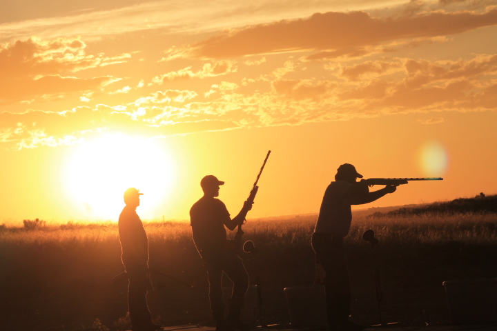 men with guns in front of sunset